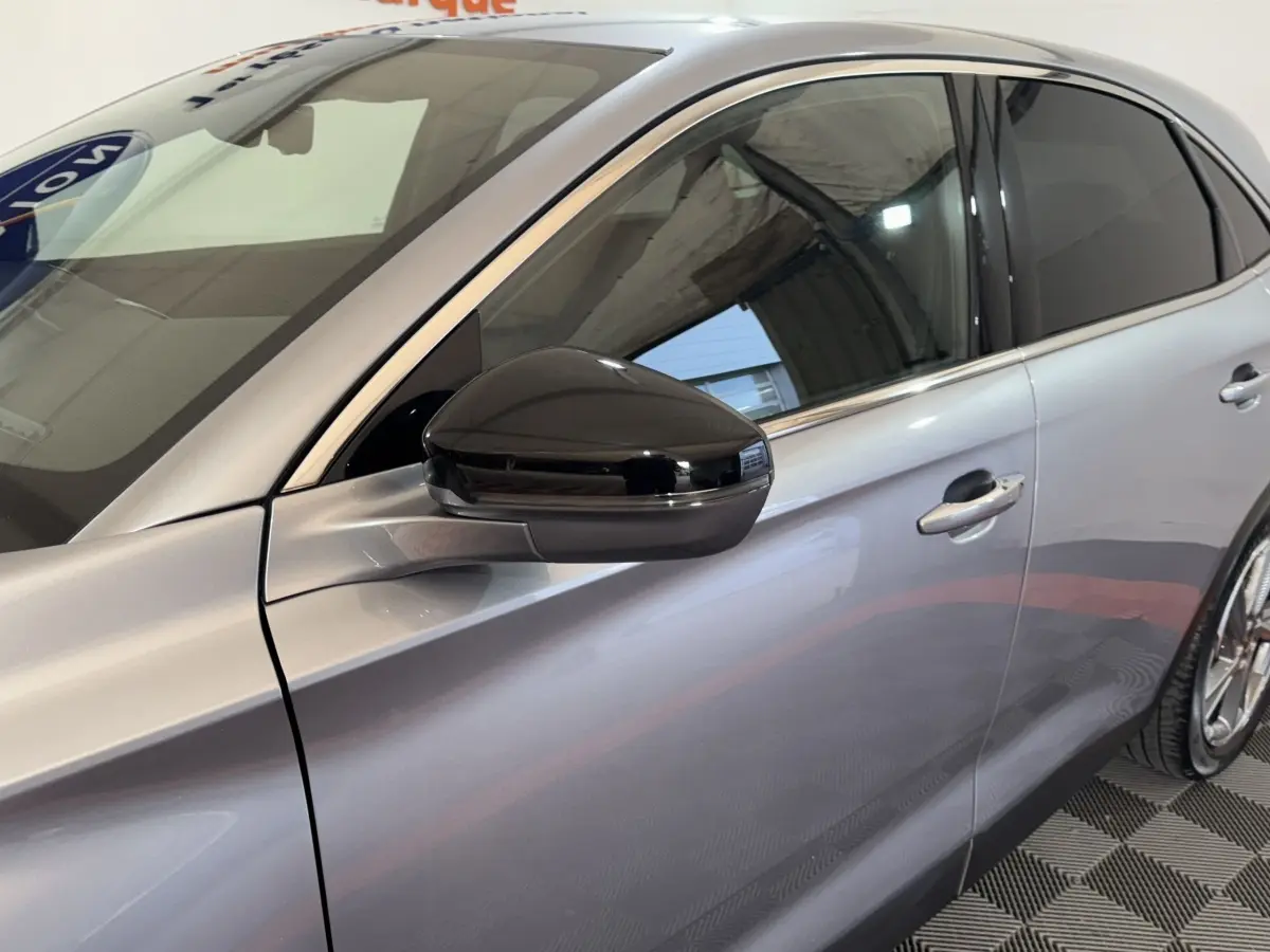 Vue latérale côté gauche du DS7 Crossback E-TENSE gris foncé avec rétroviseur noir brillant et vitres teintées.