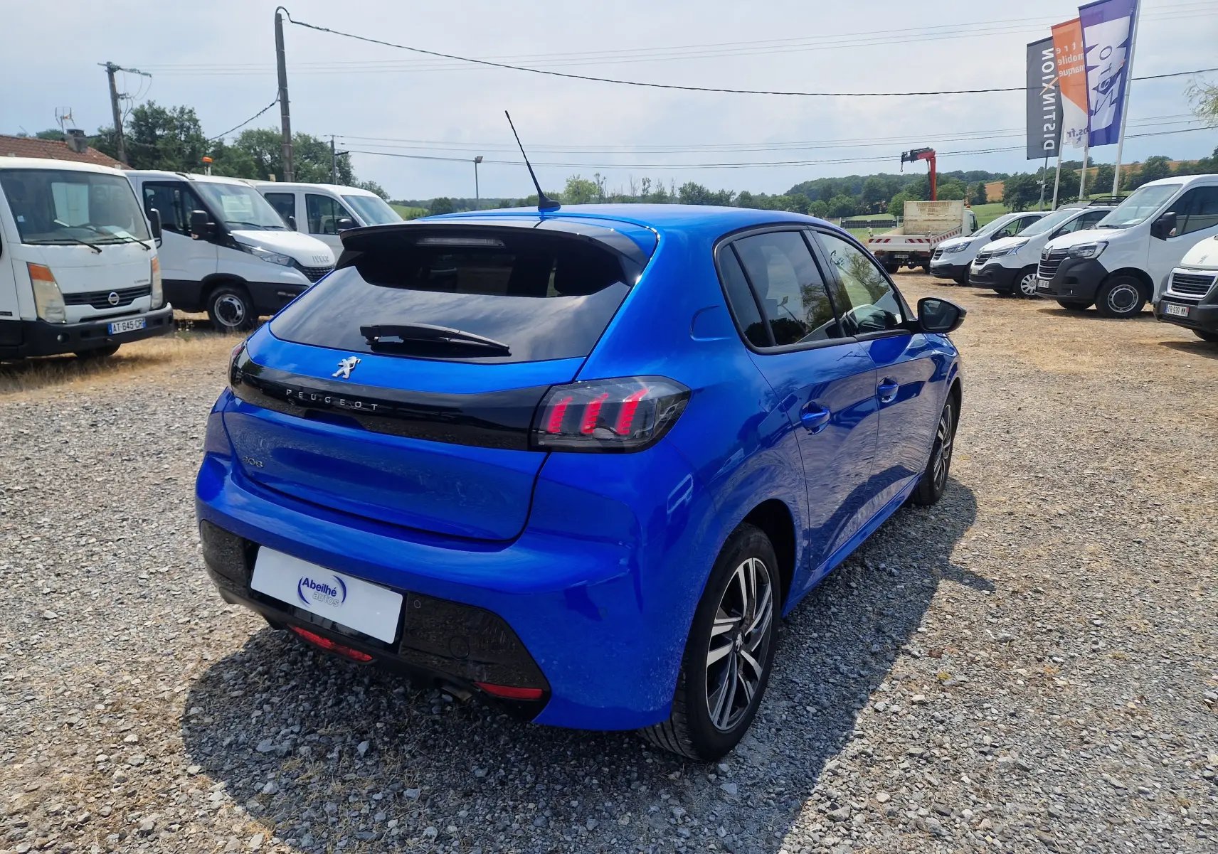 Vue 3/4 arrière droite d'une Peugeot 208 1.2 PureTech 110 Allure Pack bleu Vertigo avec feux arrière distinctifs et jantes alliage.