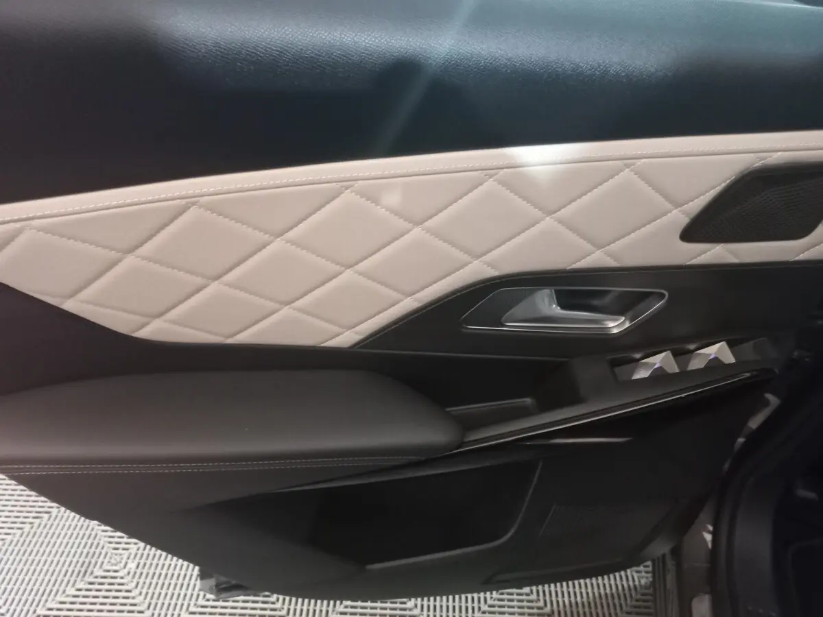 Détail de la porte intérieure côté droit du DS7 Crossback 2021 avec cuir beige matelassé et accoudoir noir.