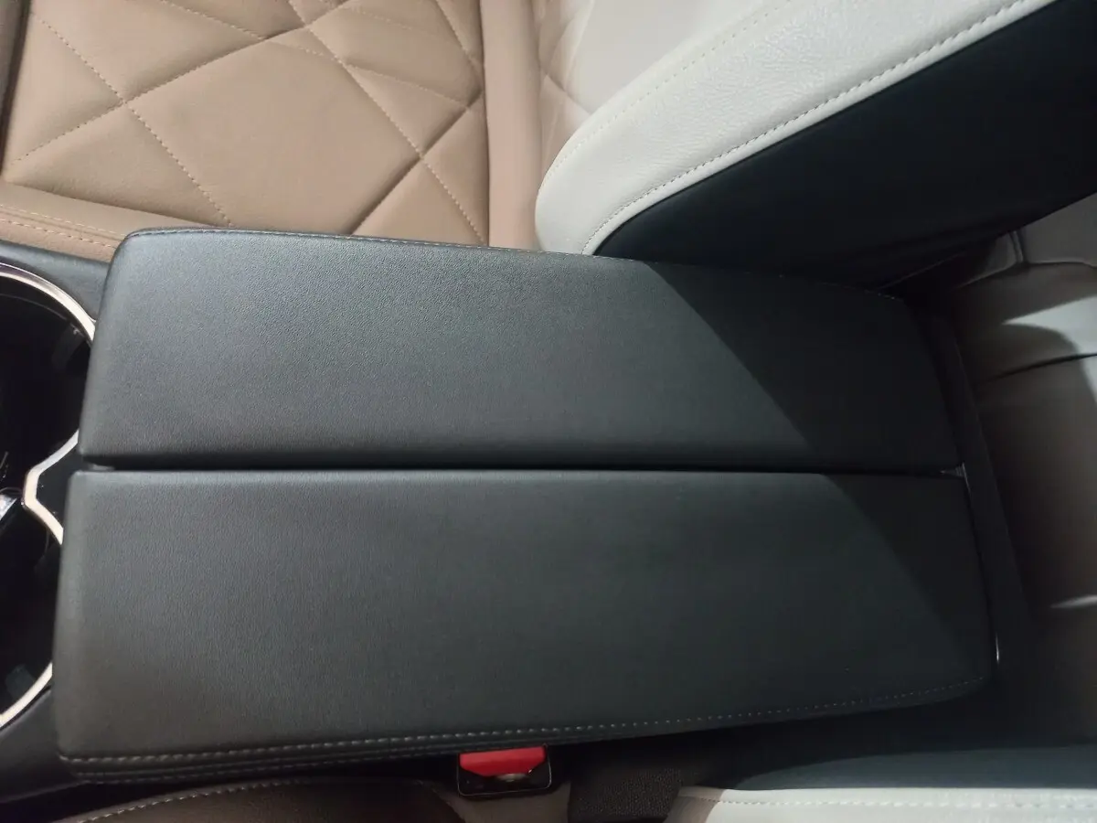 Vue rapprochée de l'accoudoir central noir et des sièges en cuir beige clair du DS7 Crossback 2021.