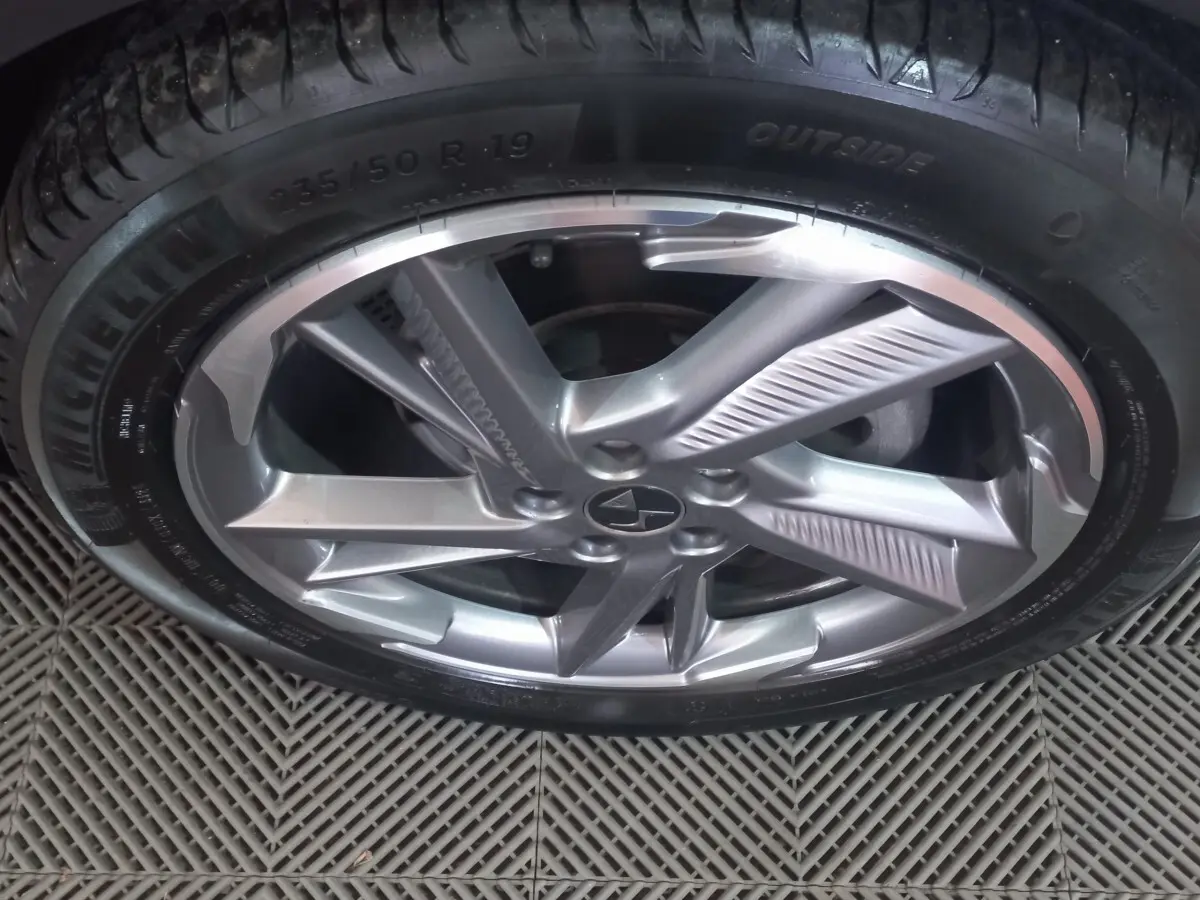 Gros plan sur la jante alliage argentée et pneu Michelin du DS7 Crossback gris foncé, vue de dessus.