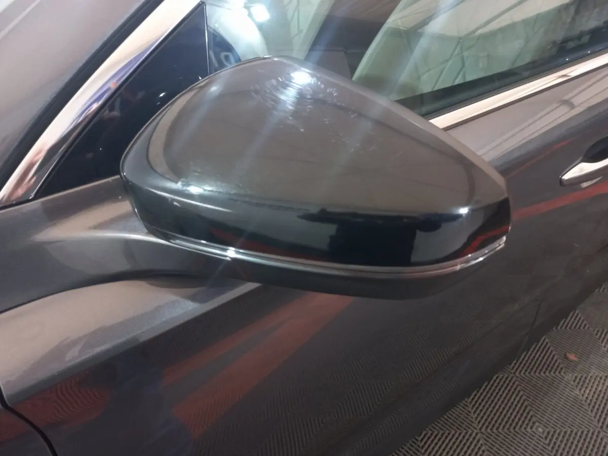 Rétroviseur côté gauche gris foncé du DS7 Crossback 2021, avec carrosserie et poignée de porte visibles en arrière-plan.