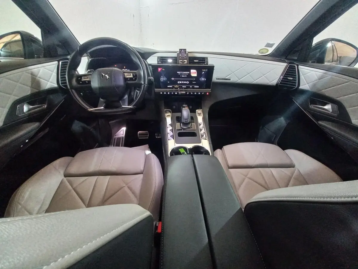 Vue intérieure avant du DS7 Crossback 2021, sièges et panneaux gris clair avec coutures losanges, tableau de bord noir.