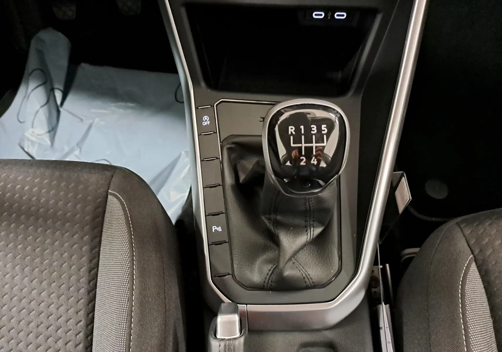 Vue plongeante sur la console centrale d'une Volkswagen Polo 2024, boîte manuelle avec levier de vitesses en cuir noir.