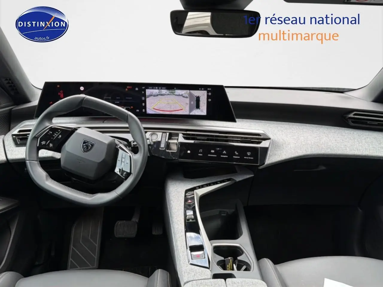 Vue intérieure du tableau de bord et volant cuir gris du Peugeot 3008 2025 avec écran tactile et caméra de recul affichée.