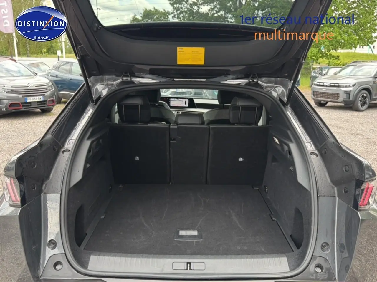 Coffre ouvert vu de l'arrière d'un Peugeot 3008 gris titane 2025, intérieur spacieux et banquette arrière rabattue partiellement.
