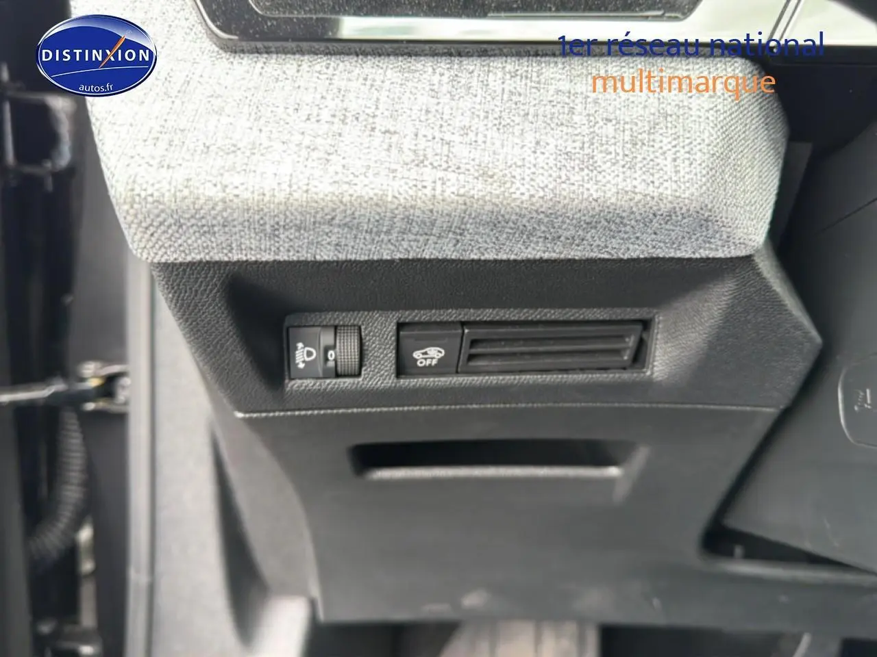 Vue rapprochée des commandes sous le tableau de bord d’un Peugeot 3008 gris titane, avec réglage phares et désactivation assistance.