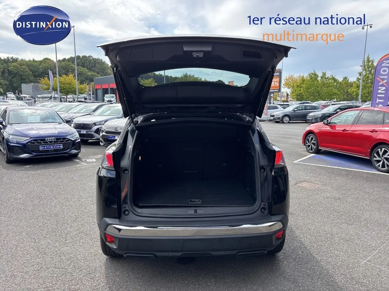 Vue arrière d’un Peugeot 3008 noir métal 2024 avec coffre ouvert sur parking multimarque.