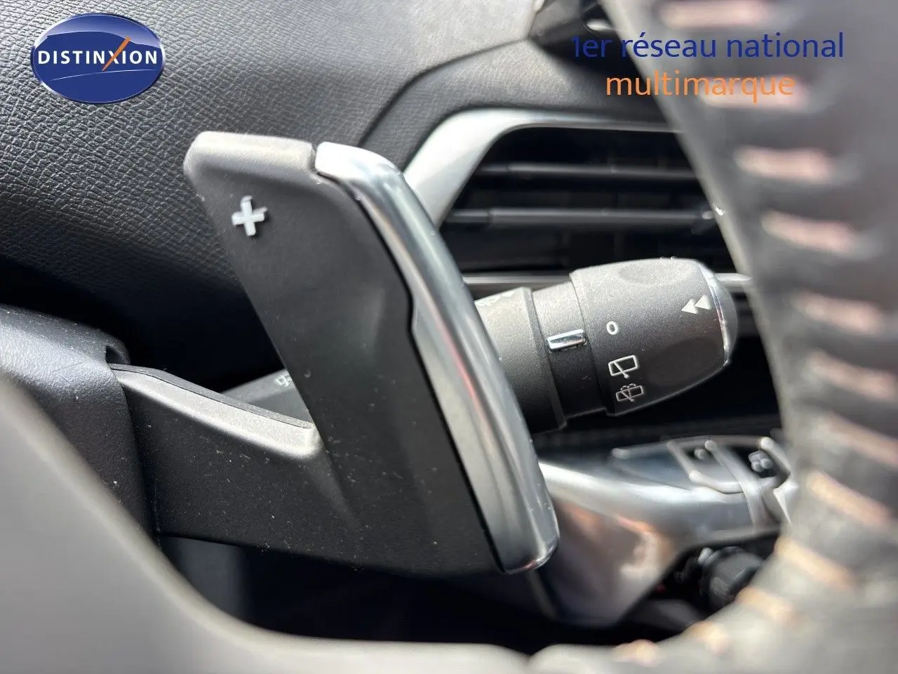 Gros plan sur la palette de changement de vitesse droite du Peugeot 3008 noir métal, intérieur avec commandes au volant.