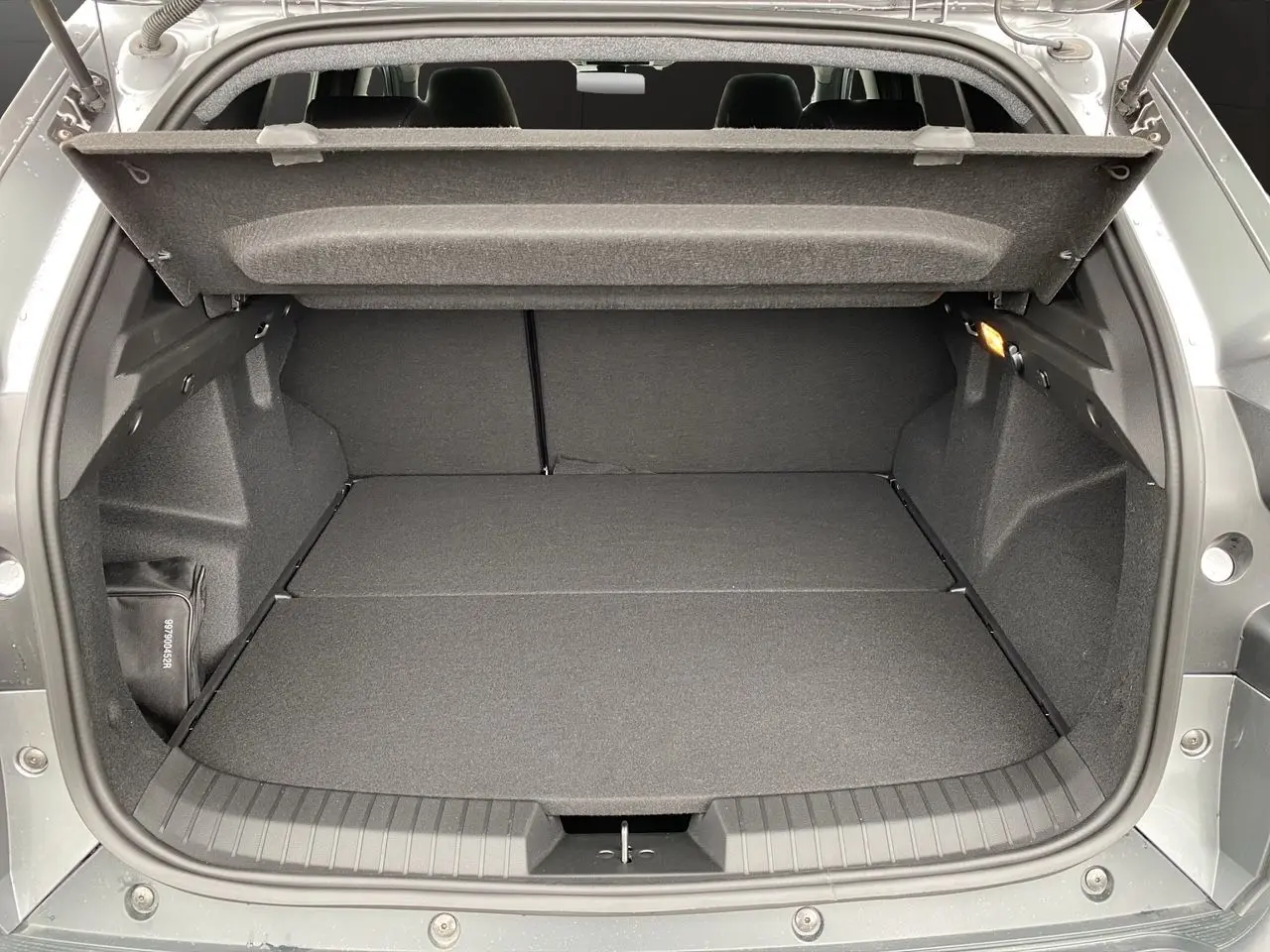 Coffre ouvert du Dacia Duster gris schiste, vue arrière montrant un espace de chargement plat et spacieux.