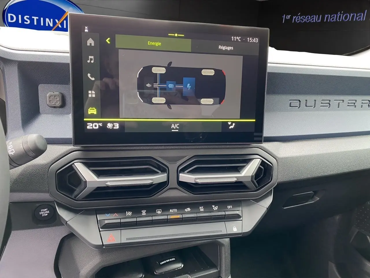 Tableau de bord du Dacia Duster hybride 2025 avec écran tactile affichant l'énergie et aérateurs hexagonaux noirs.