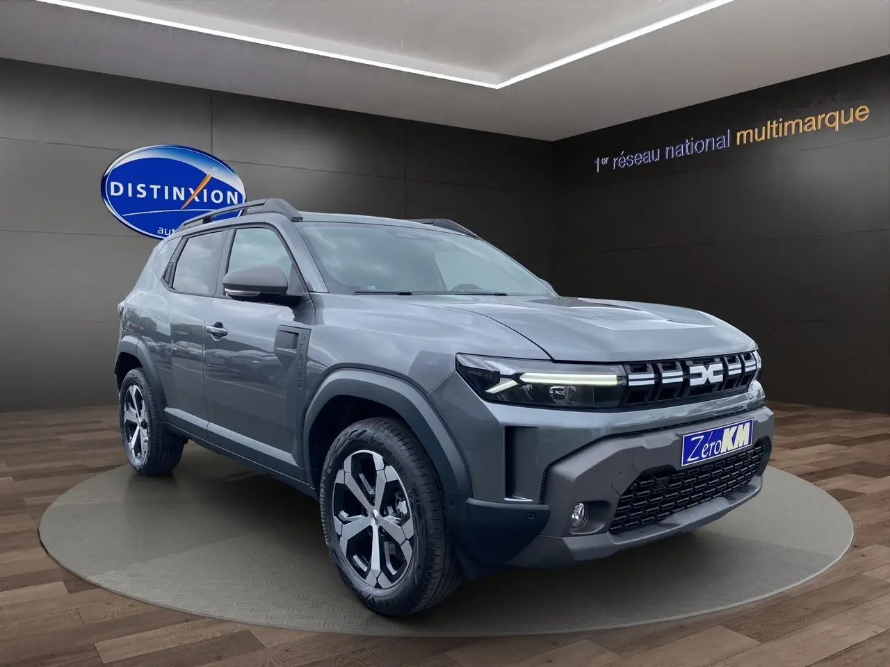 Vue 3/4 avant du Dacia Duster gris schiste hybride 140 Journey 4x2 avec jantes alliage et pack City visible.