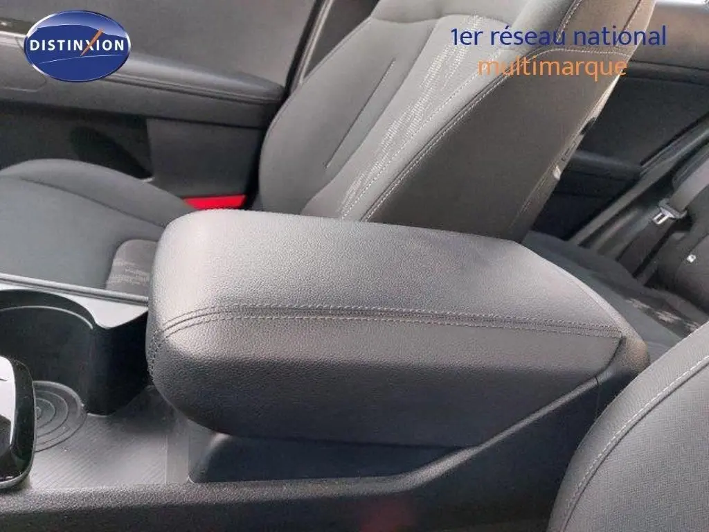 Gros plan sur l'accoudoir central en cuir noir et les sièges gris foncé à l'intérieur du Kia Sportage hybride 2024.