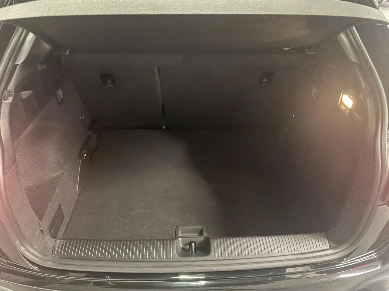 Coffre ouvert vu de face d’un Audi Q2 noir métallisé 2023, espace de chargement vide avec éclairage intérieur.