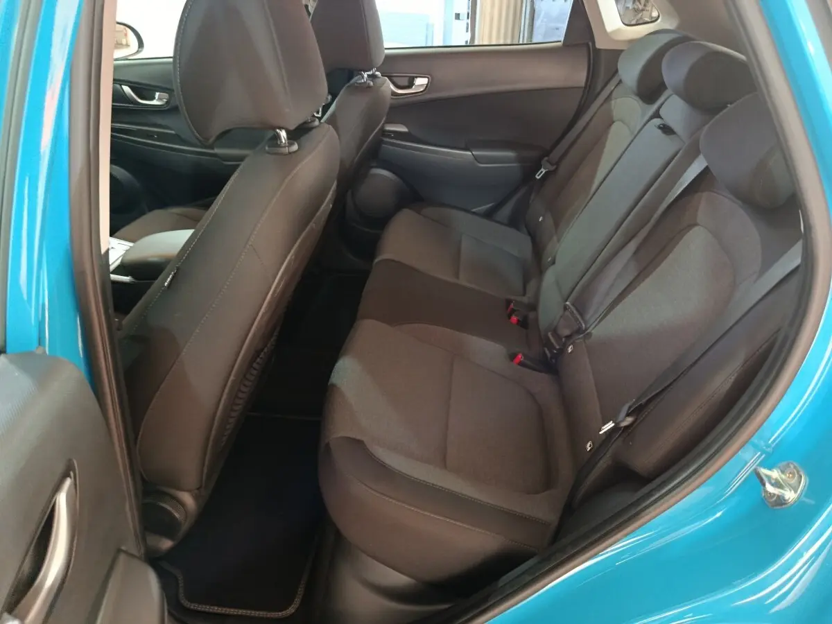 Vue intérieure côté droit sur la banquette arrière noire du Hyundai Kona électrique bleu 2022 avec ceinture de sécurité visible.
