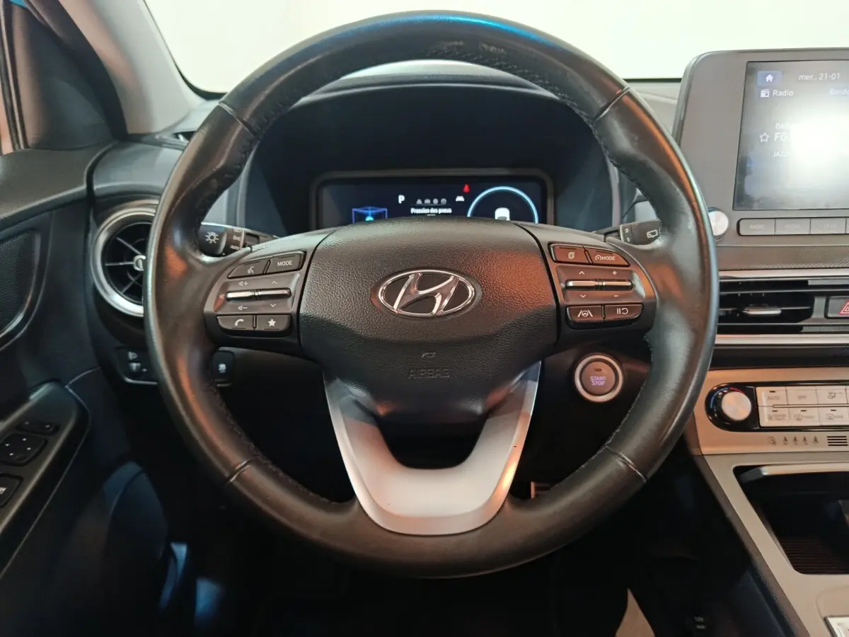 Vue intérieure centrée sur le volant noir de la Hyundai Kona électrique 2022 avec tableau de bord et écran tactile.