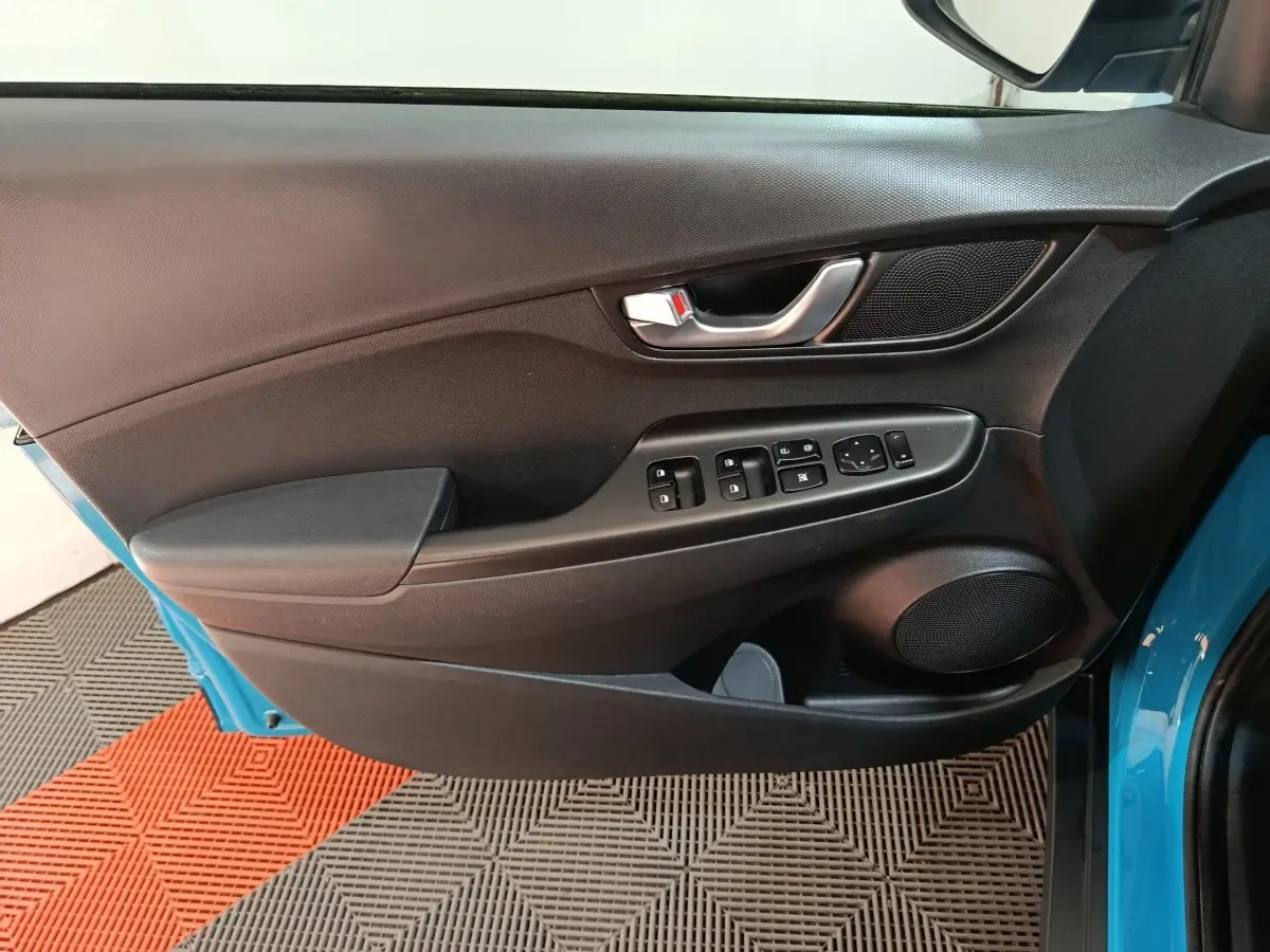 Vue rapprochée de la porte avant gauche noire avec commandes électriques sur Hyundai Kona bleu électrique 2022.