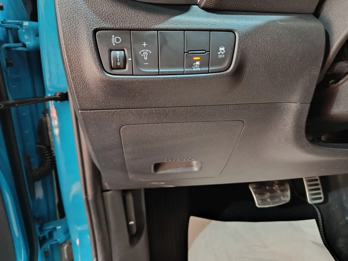 Détail des commandes d’éclairage et de stabilité côté gauche, intérieur noir, portière bleu visible Hyundai Kona électrique 2022.