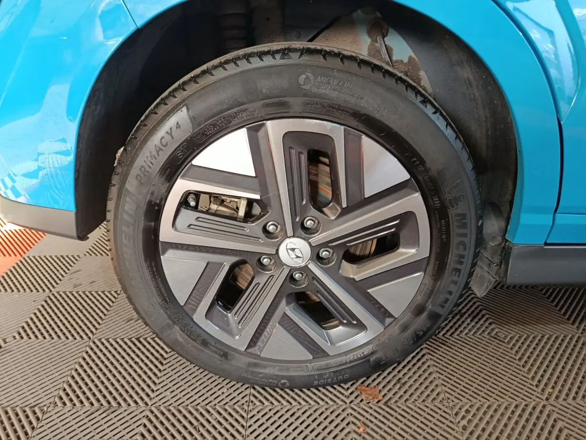 Gros plan sur la roue avant droite d’un Hyundai Kona électrique bleu, avec jante alliage et pneu Michelin.