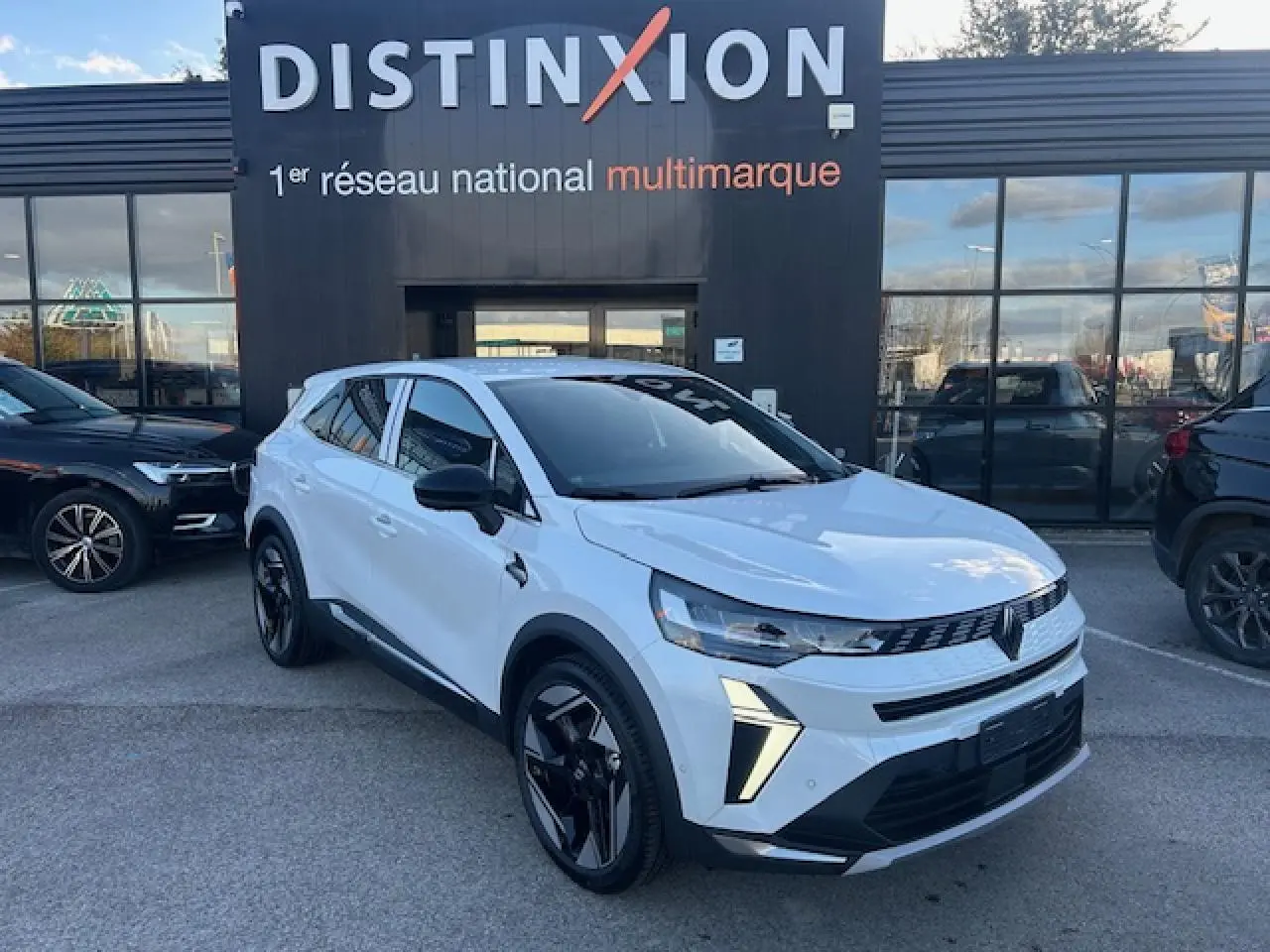 Renault Symbioz blanc nacré vue 3/4 avant droit, calandre 3D et jantes alliage noires distinctives.