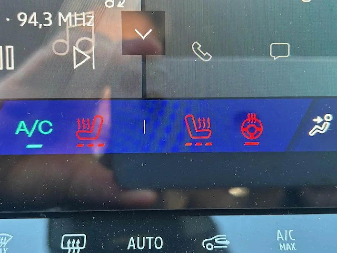 Gros plan sur l'écran tactile intérieur du Renault Symbioz blanc nacré, affichant les commandes de chauffage des sièges et volant.