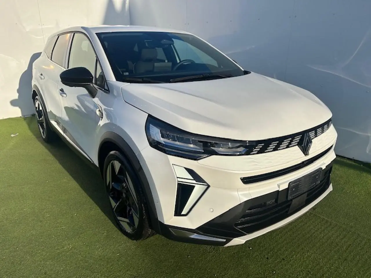 Renault Symbioz blanc nacré en 3/4 avant droit, avec calandre noire et jantes alliage noires distinctives.