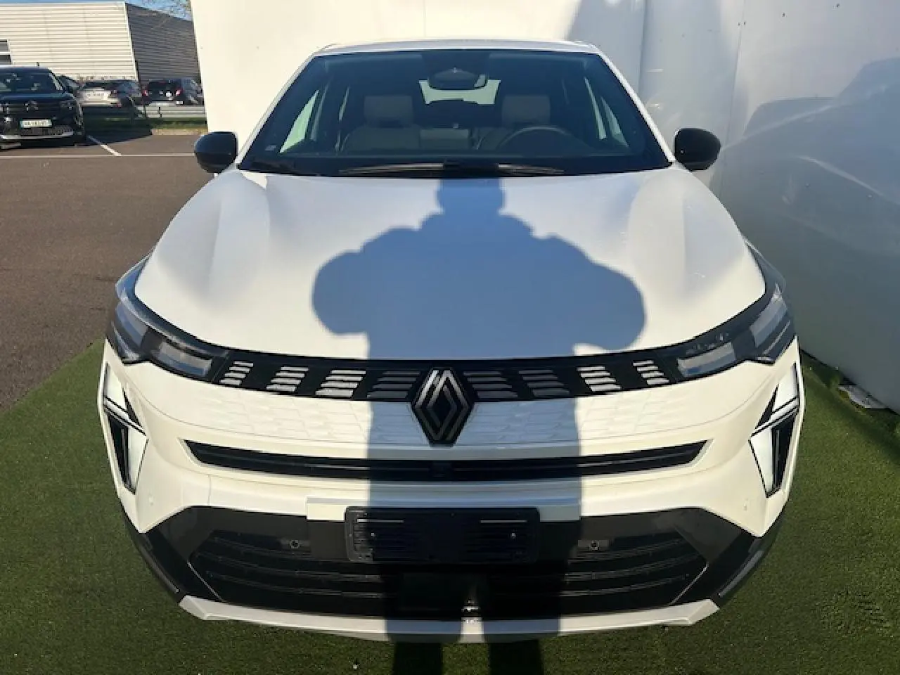 Vue avant d'une Renault Symbioz blanc nacré avec calandre noire et logo central, éclairage LED distinctif.