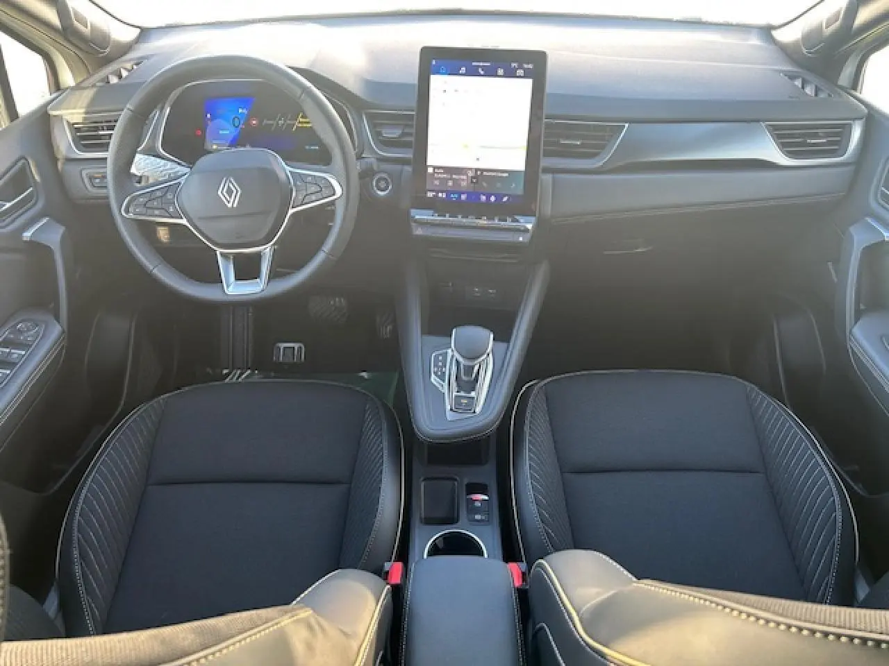 Vue intérieure avant du Renault Symbioz 2025, tableau de bord noir avec écran tactile vertical et volant multifonction.