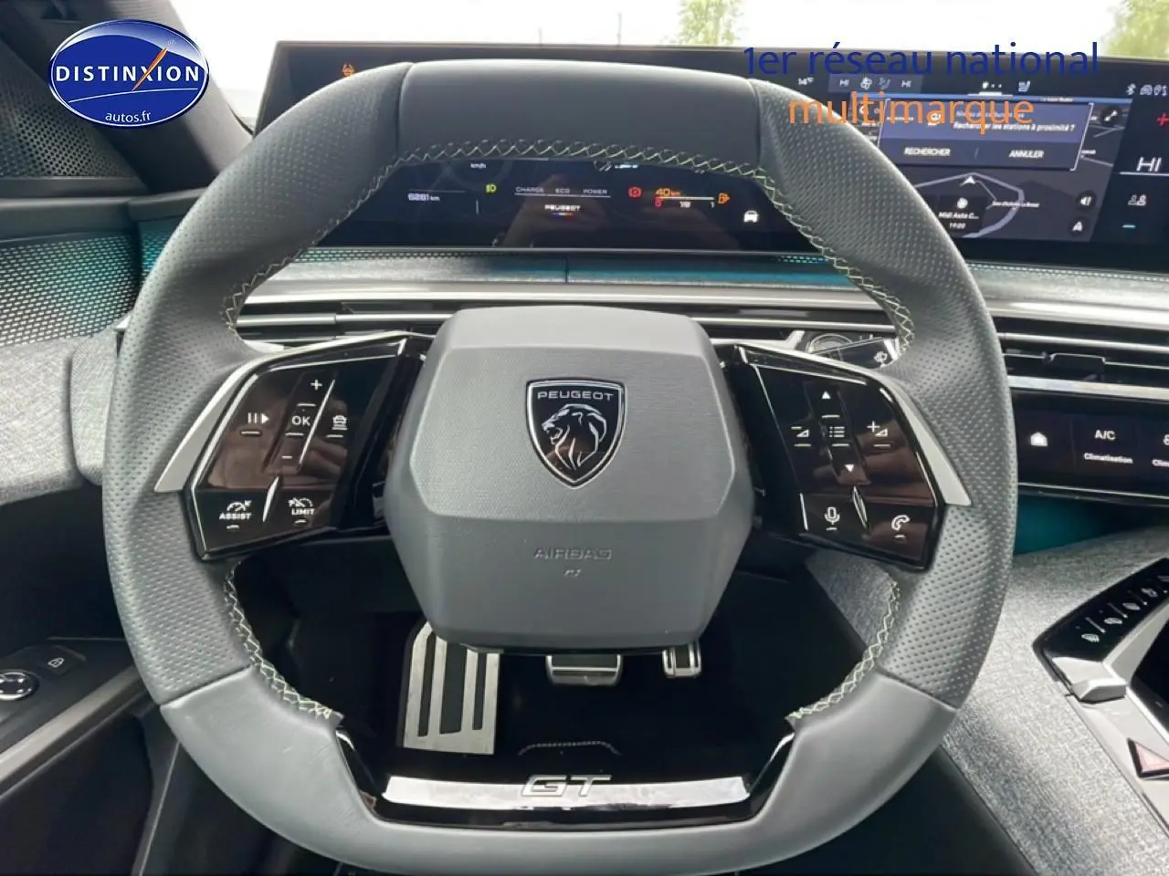 Volant cuir multifonction vu de face dans un Peugeot 3008 blanc 2025, avec logo et pédalier sport visibles.