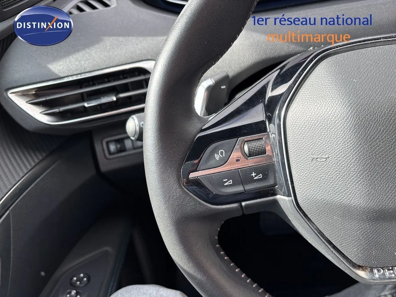 Gros plan sur le volant multifonction en cuir noir du Peugeot 3008 Hybrid 2024, avec commandes audio intégrées.