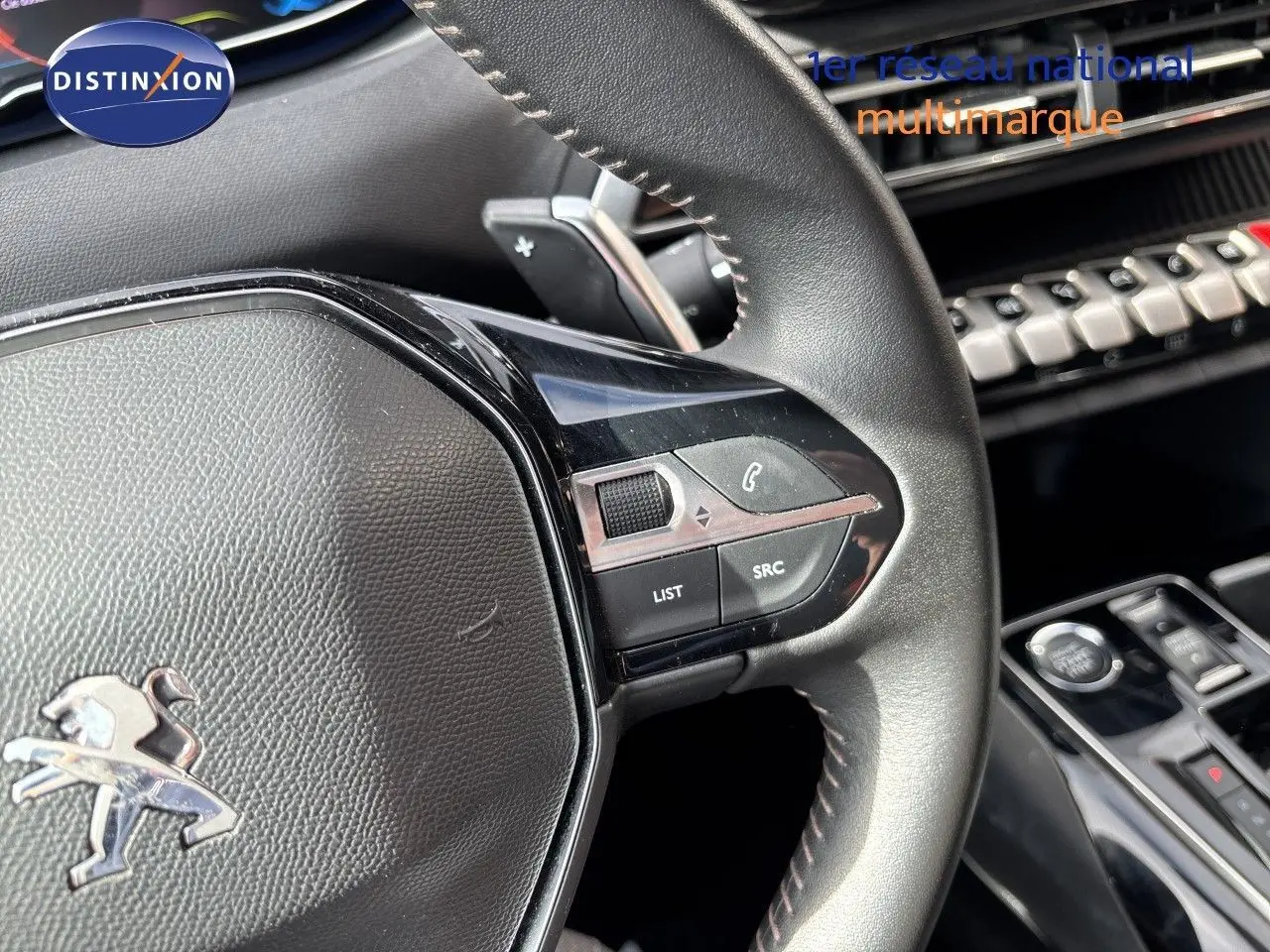 Gros plan sur le volant cuir noir du Peugeot 3008 Hybrid 2024, avec commandes intégrées et tableau de bord partiel visible.