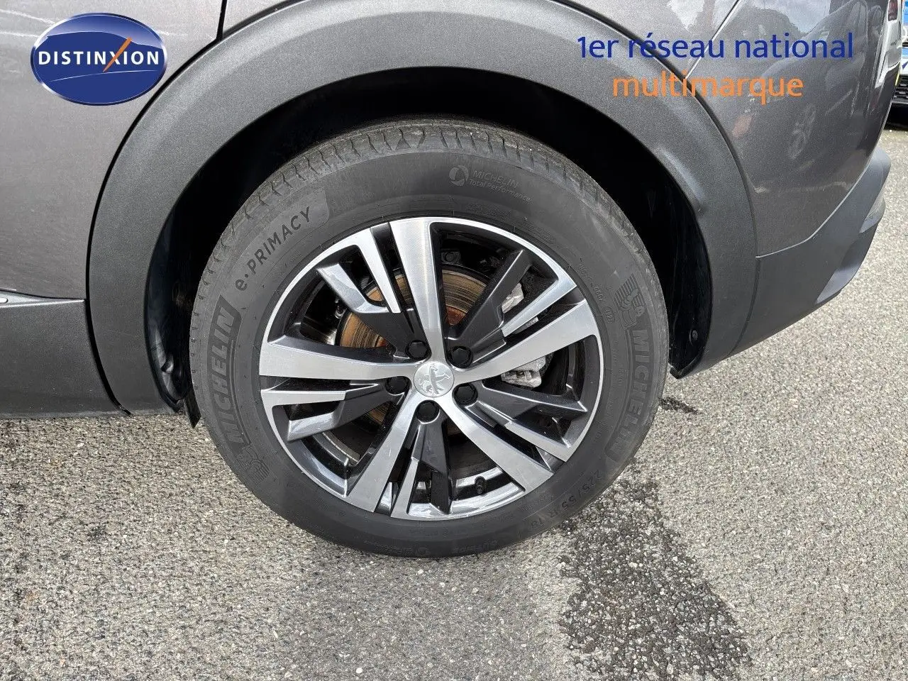 Gros plan sur la roue avant gauche du Peugeot 3008 gris platinium, mettant en valeur la jante alliage bicolore et le pneu Michelin.
