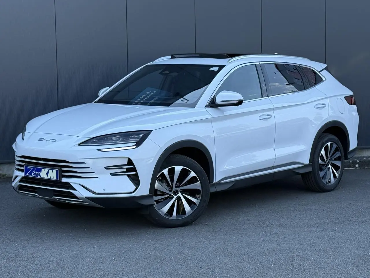 Vue 3/4 avant droite du SUV BYD SEAL U blanc Snow White avec jantes alliage bicolores et barres de toit en aluminium.