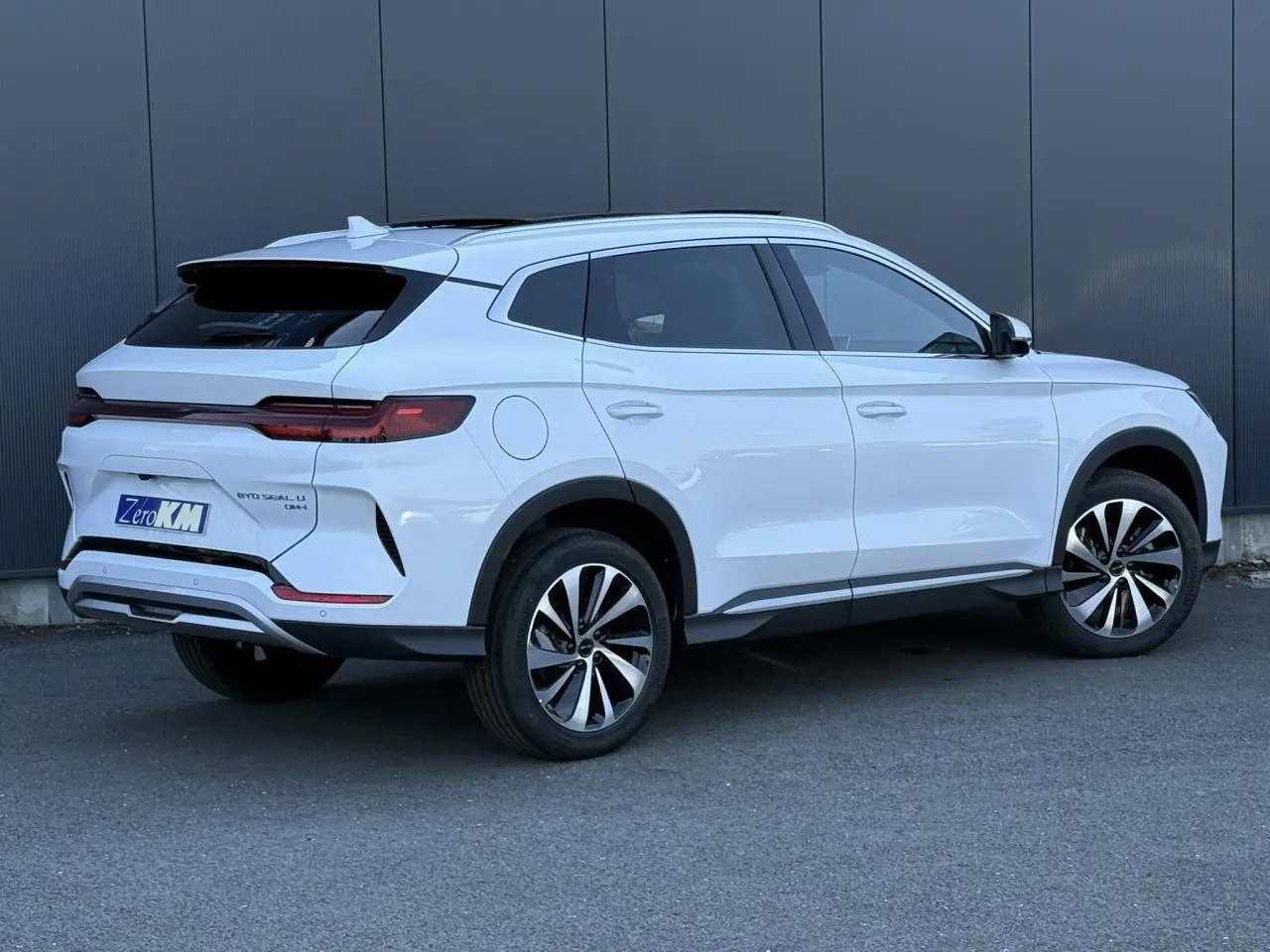 Vue 3/4 arrière droite du SUV BYD SEAL U 1.5 DM-i 218 Boost en blanc Snow White avec jantes bicolores et toit panoramique.