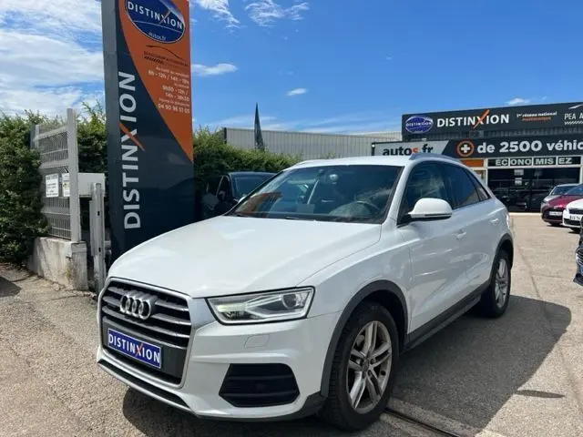 Audi Q3 blanc vue 3/4 avant droit, version 2.0 TDI Ambition Luxe 2015, sur parking devant enseigne Distinxion.