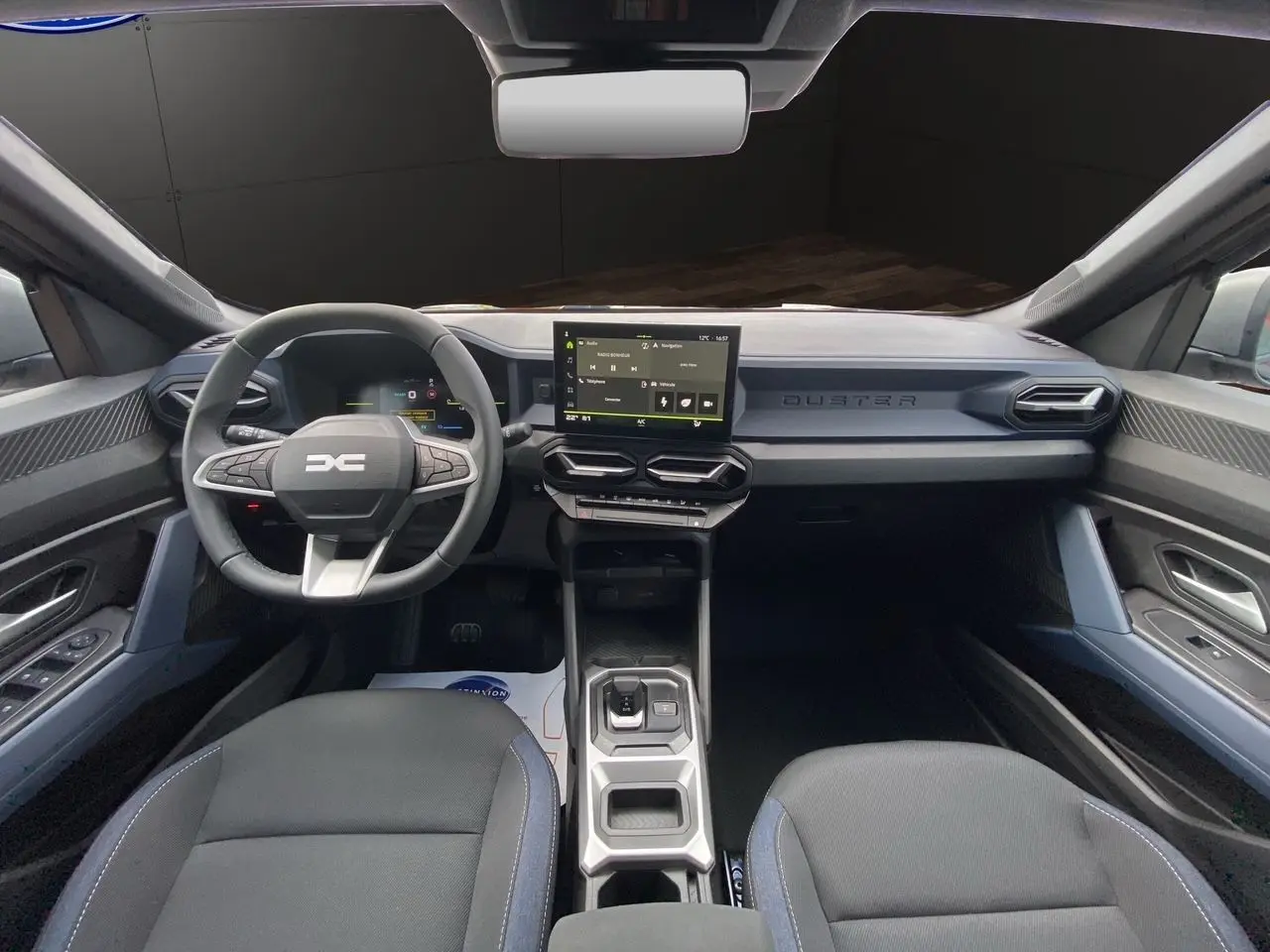 Intérieur noir et bleu du Dacia Duster 2025, vue frontale du tableau de bord avec écran tactile central.