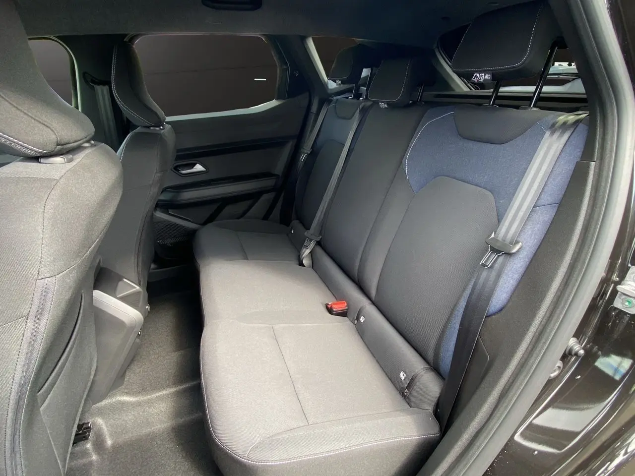 Vue intérieure côté droit des sièges arrière en tissu noir et bleu du Dacia Duster hybride 2025.