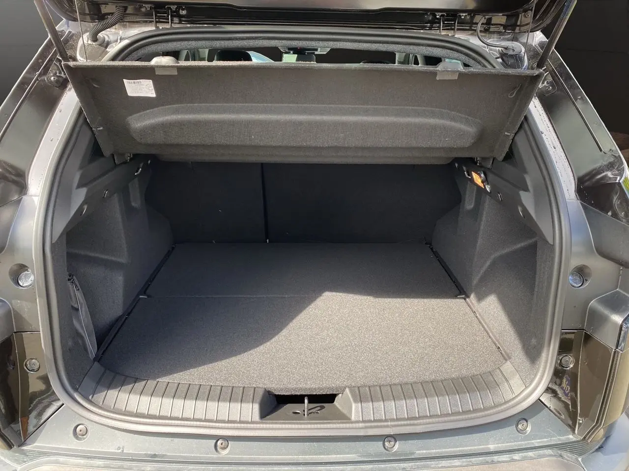 Coffre ouvert du Dacia Duster hybride noir 2025, montrant un espace de chargement plat et bien fini.