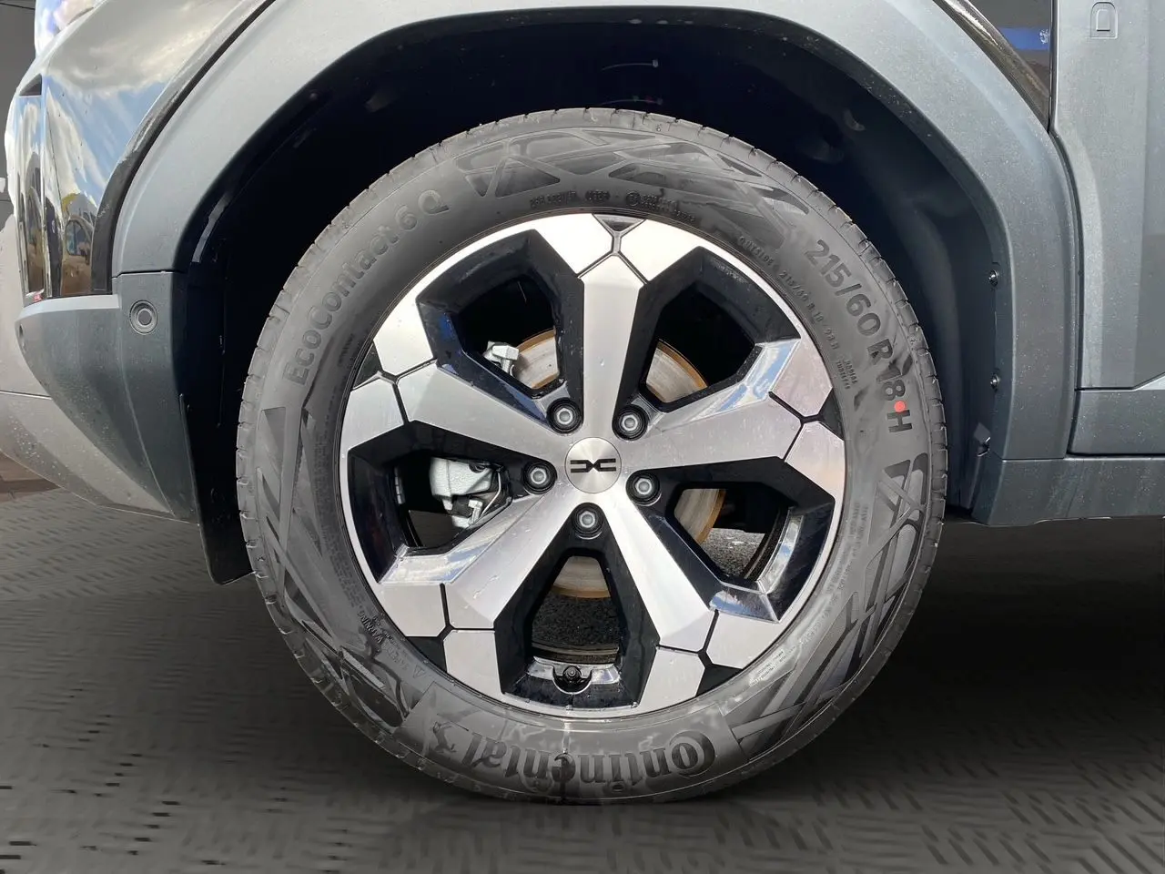 Gros plan sur la roue avant droite du Dacia Duster hybride noir, avec jante alliage bicolore et pneu Continental.