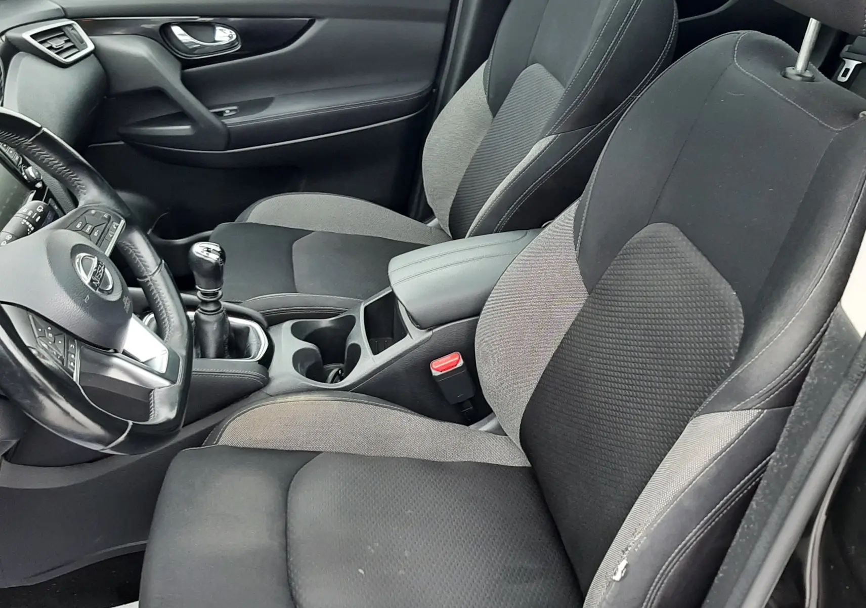 Vue intérieure côté conducteur du Nissan Qashqai DCI 115 N-Connecta 2020, sièges tissu gris et noir, volant et levier de vitesses manuelle.