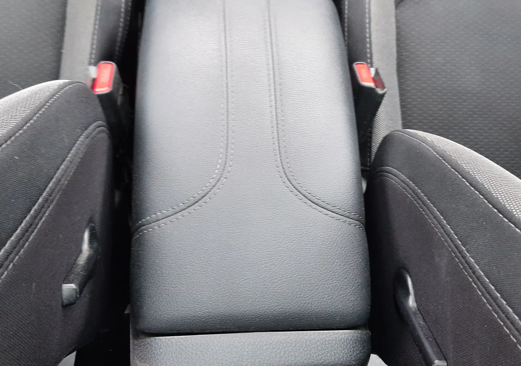 Vue rapprochée de l'accoudoir central noir en cuir entre les sièges avant en tissu gris du Nissan Qashqai DCI 115 N-Connecta 2020.