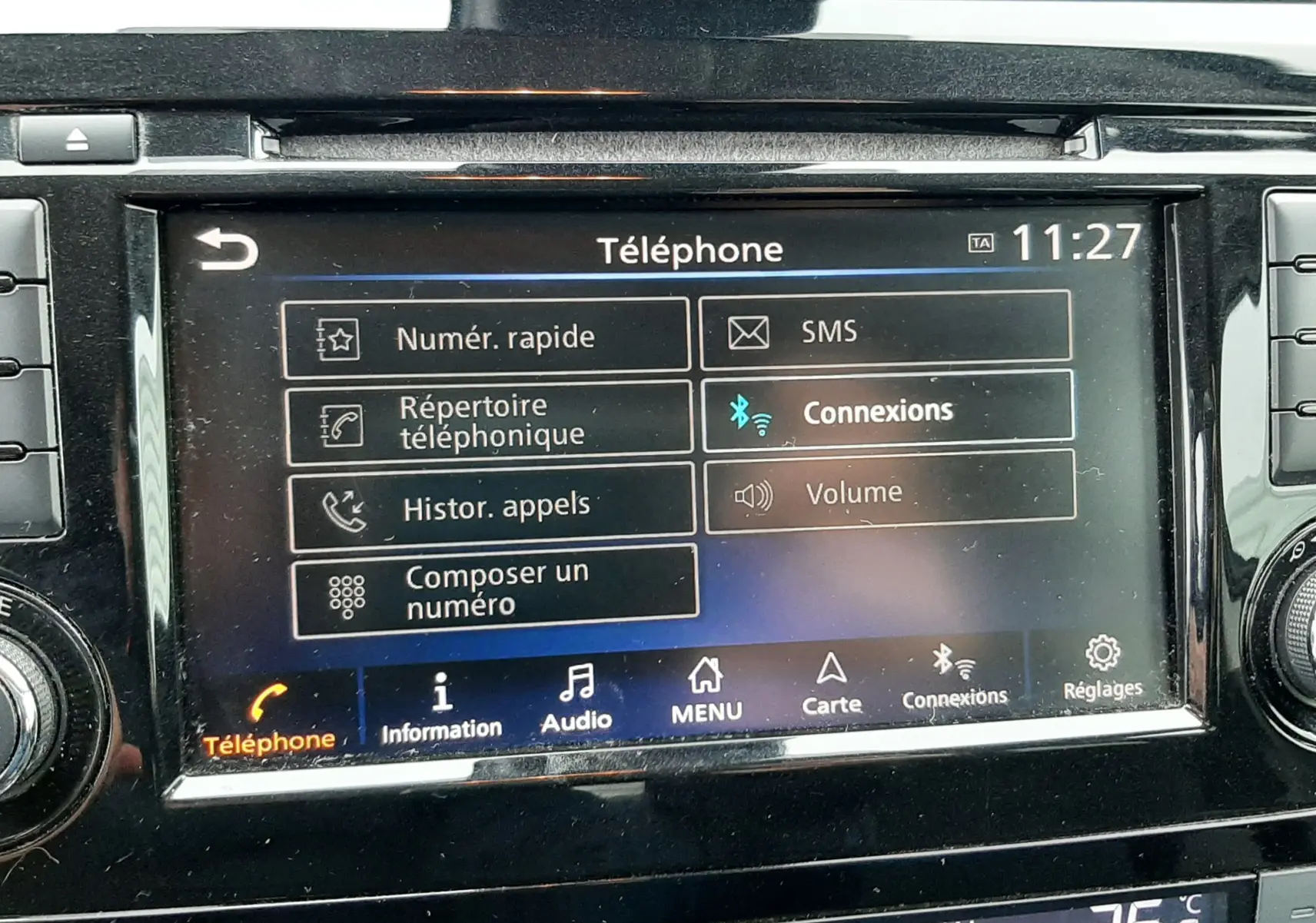 Écran tactile central du Nissan Qashqai noir 2020, affichant le menu téléphone avec commandes climatisation en dessous.