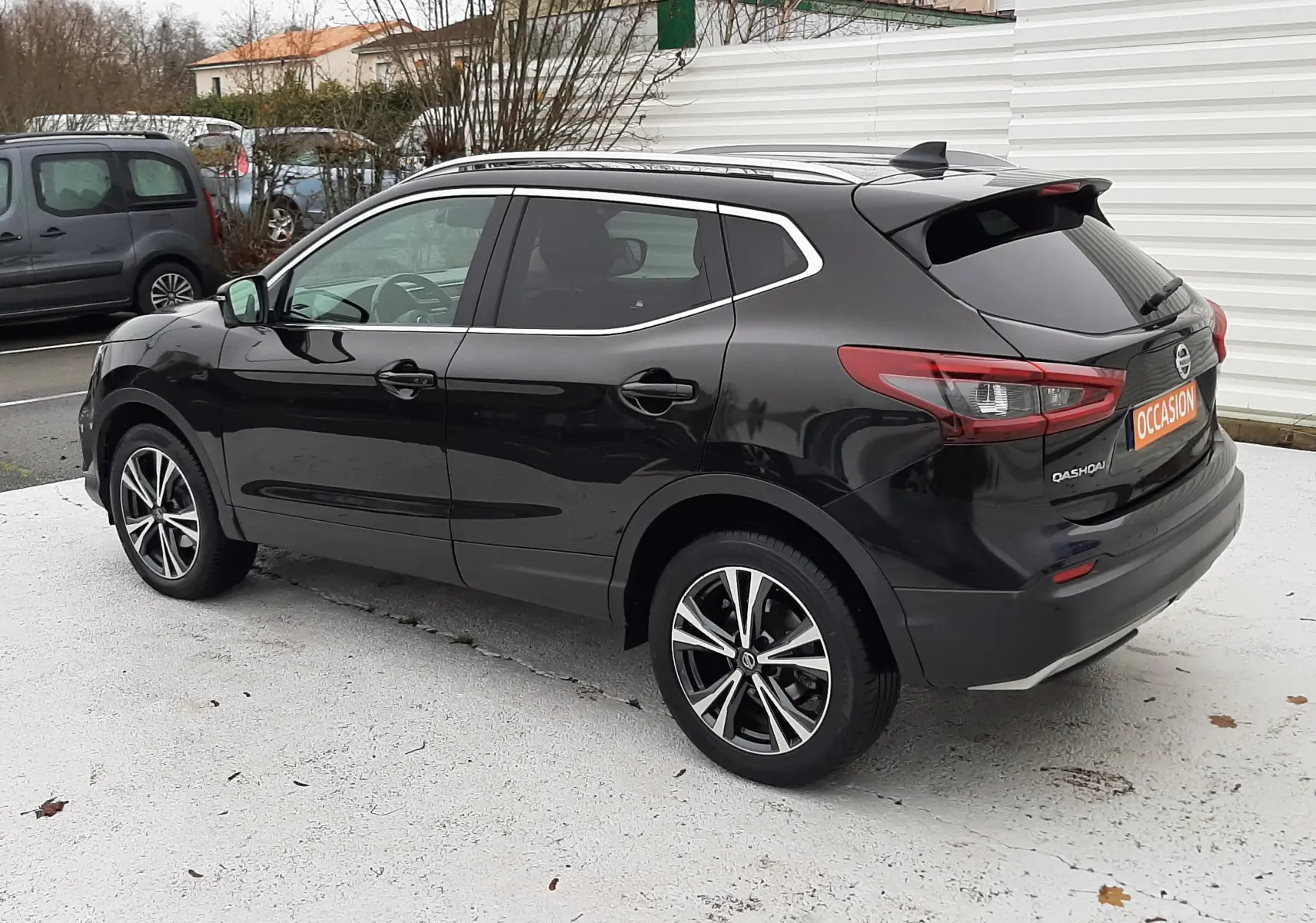 Vue 3/4 arrière droite d'un Nissan Qashqai noir 2020 avec jantes alliage bicolores et vitres teintées.