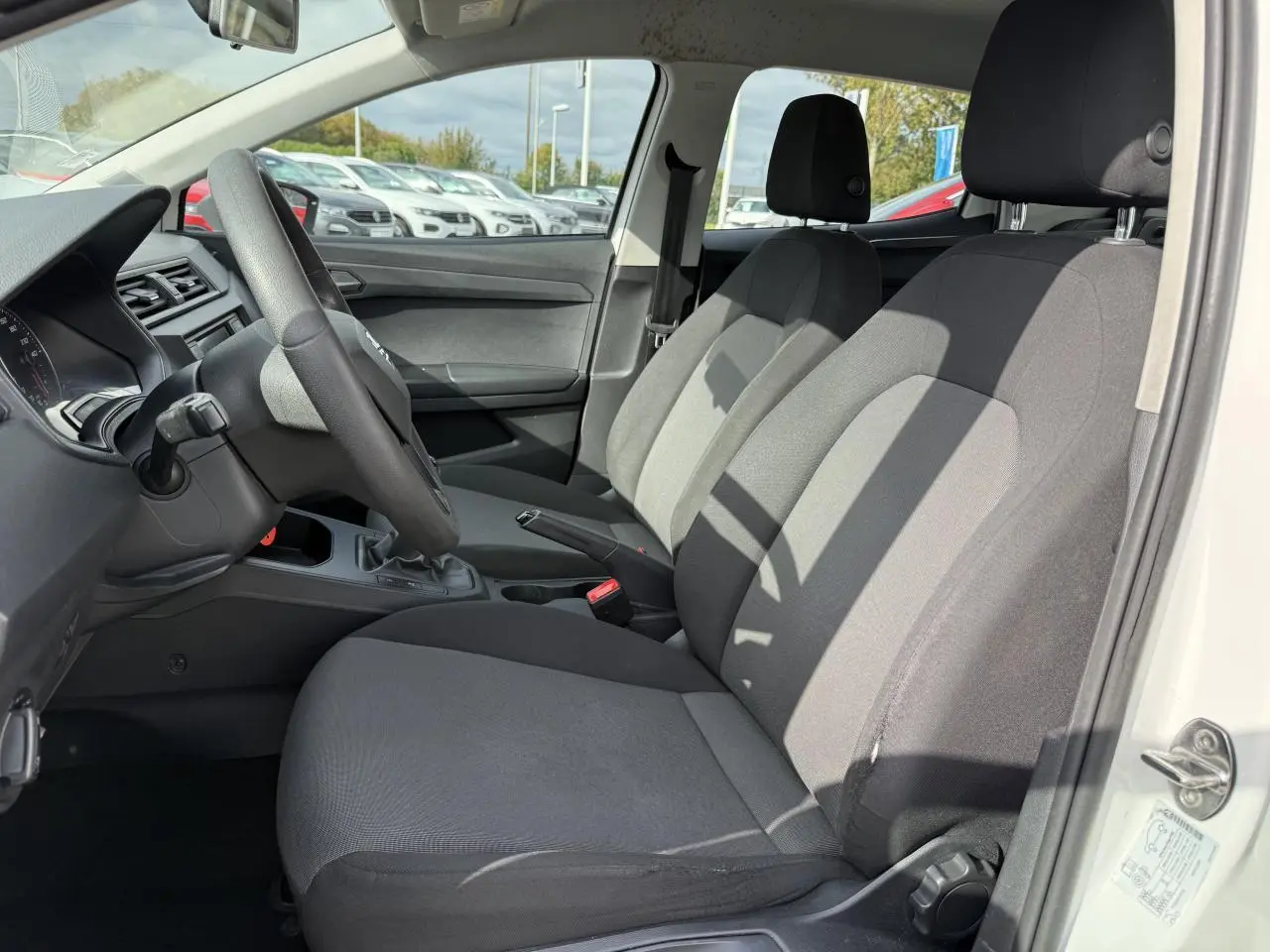 Intérieur avant droit de la SEAT Ibiza 1.6 TDI 2019 blanc Candy, sièges tissu gris et volant multifonction noir.