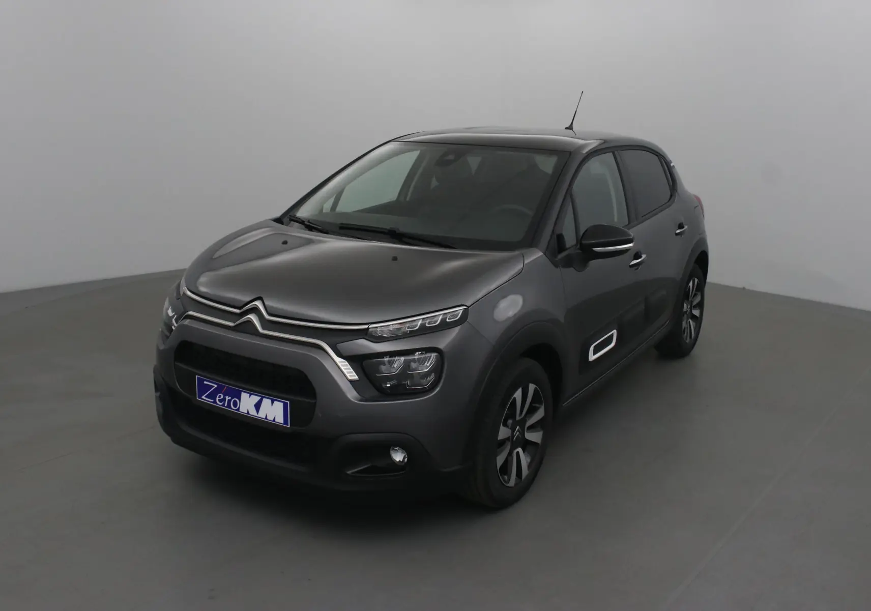 Citroën C3 gris platinium et noir en 3/4 avant droit, avec protections latérales blanches et jantes bi-ton.