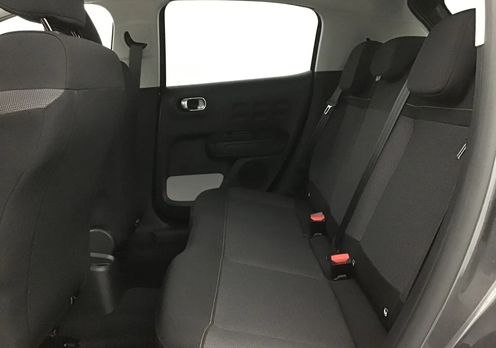 Vue intérieure sur les sièges arrière noirs de la Citroën C3 2022, avec ceinture de sécurité et porte côté gauche visible.