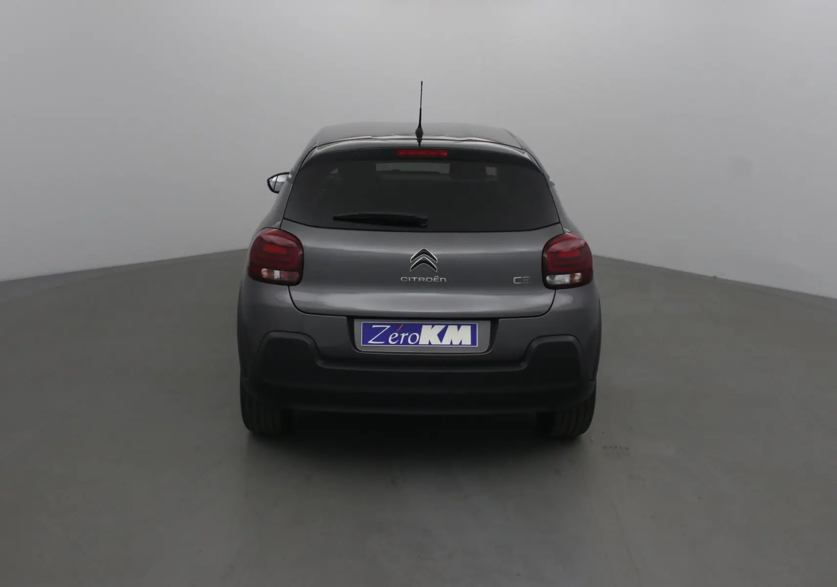 Vue arrière d'une Citroën C3 2022 gris platinium avec feux arrière rouges et plaque Zero KM visible