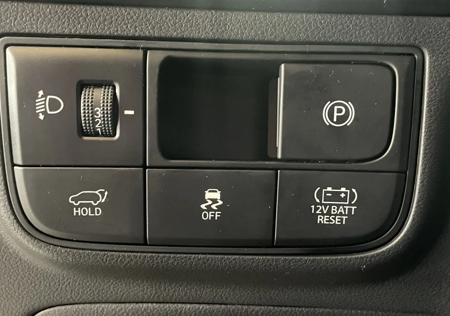 Gros plan sur les boutons de commande intérieurs du Hyundai Tucson gris Ecotronic, incluant frein à main électronique et contrôle de stabilité.