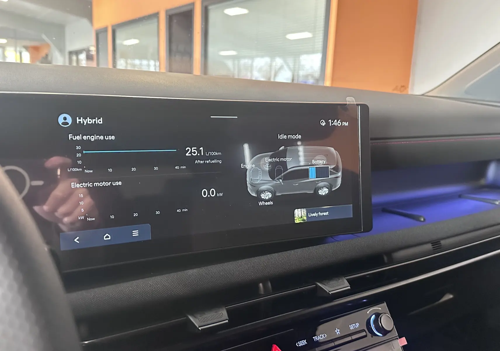 Vue intérieure du tableau de bord du Hyundai Tucson 2025 hybride, avec écran tactile affichant l'usage moteur et éclairage d'ambiance bleu.