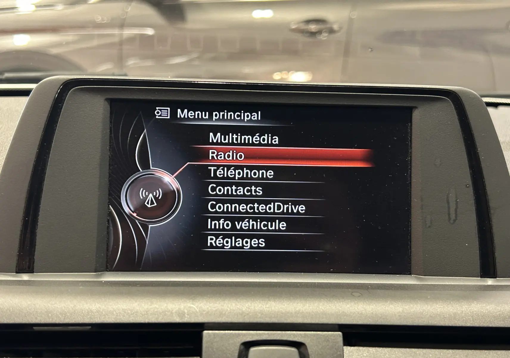 Écran central du système multimédia d'une BMW Série 1 16d gris, affichant le menu principal avec l'option Radio sélectionnée.